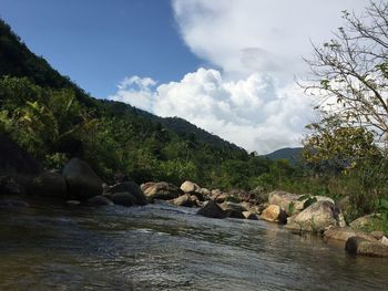 Rocks by river against sky