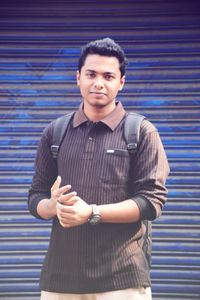 Portrait of young man standing against shutter