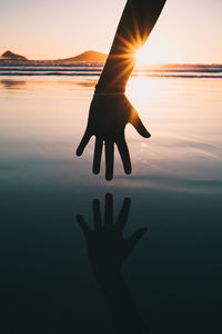 Silhouette hand against sky during sunset