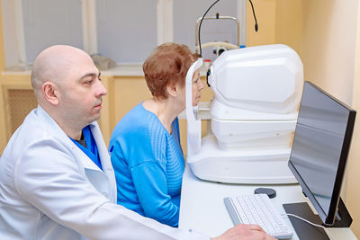 A male ophthalmologist checks the eyesight of an adult woman using a modern device