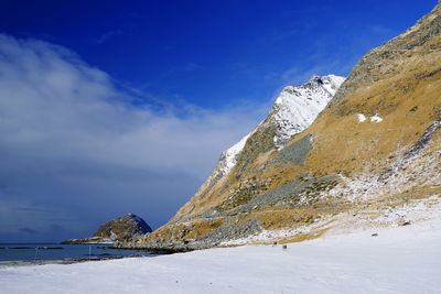 Scenic view of sea and snowcapped mountains against blue sky