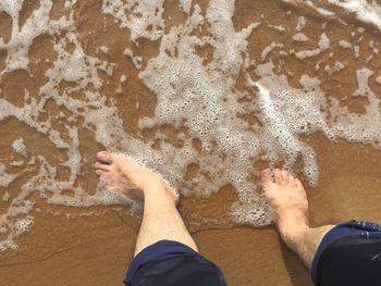 Low section of man standing on beach