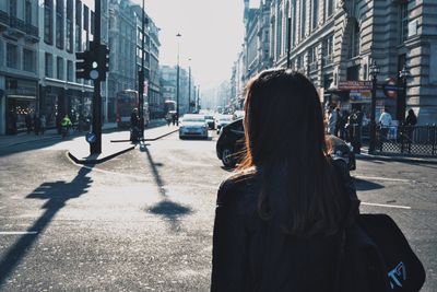 Woman walking on road against buildings