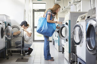 Full length of male and female university students doing laundry at laundromat