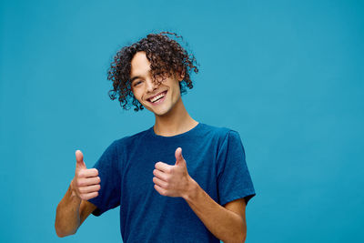 Young woman gesturing against blue background