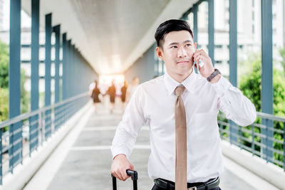 Businessman talking on mobile phone while standing on bridge