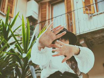 Portrait of young woman wearing hat standing against building