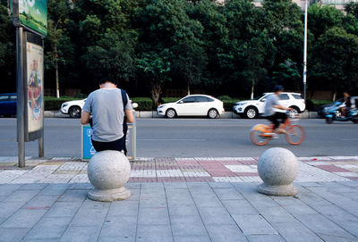 Rear view of man on street against trees in city