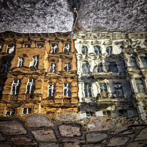 Reflection of building in water puddle on footpath