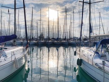 Sailboats moored at harbor during sunset