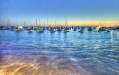 Boats moored in calm blue sea against sky