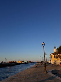 Street by buildings against clear blue sky