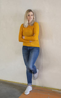 Full length portrait of woman leaning on wall