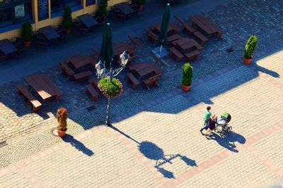 High angle view of man and woman walking by sidewalk cafe on sunny day