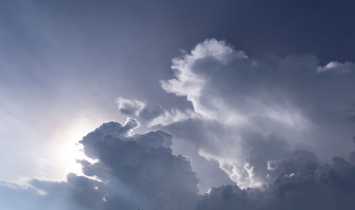 Low angle view of sunlight streaming through clouds