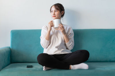 Young woman sitting on sofa at home