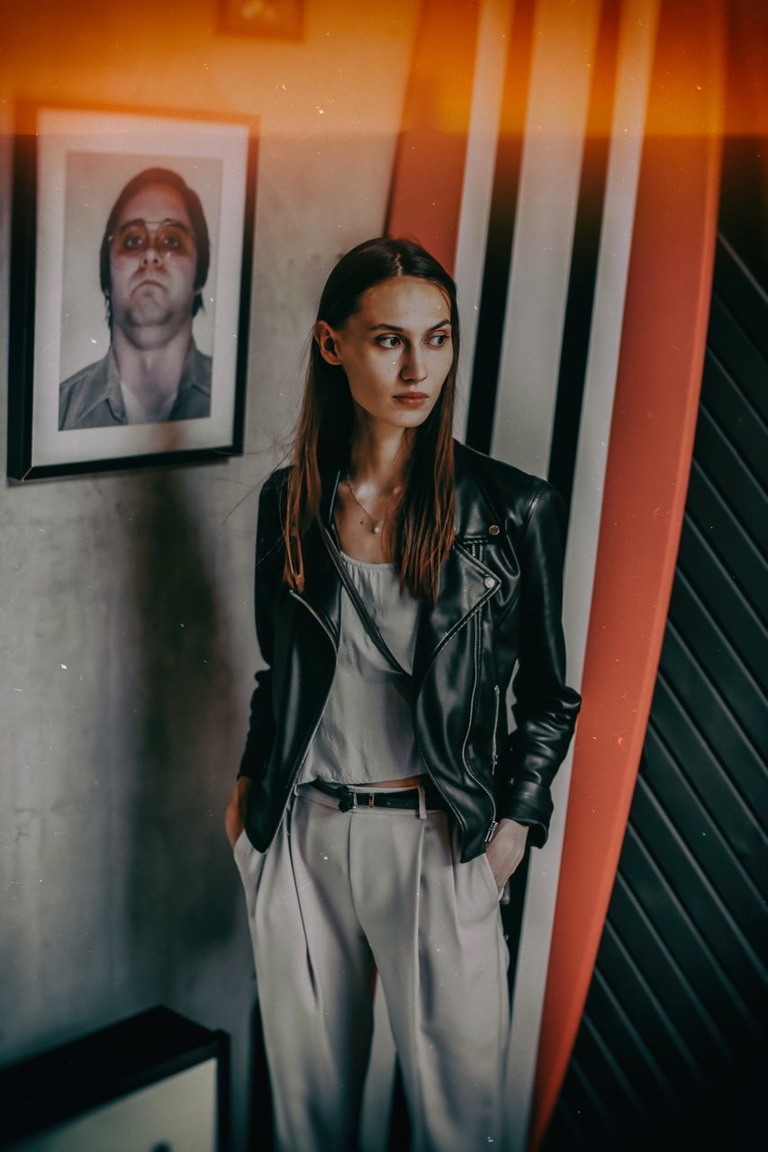 young adult, indoors, front view, one person, standing, three quarter length, real people, young women, portrait, looking at camera, adult, looking, casual clothing, clothing, business, wall - building feature, women, hairstyle, beautiful woman, contemplation