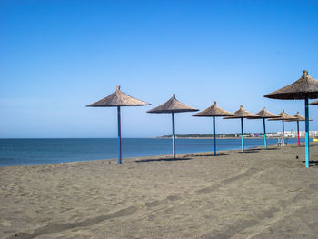 Parasols on beach against clear blue sky