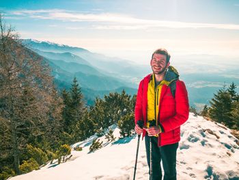 Portrait of smiling woman standing on mountain during winter