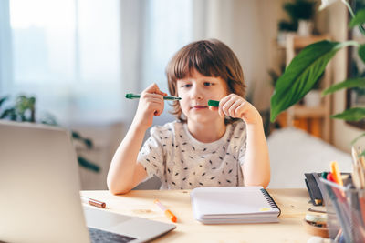 Distance learning online education. kid boy studying at home with laptop and doing school homework. 