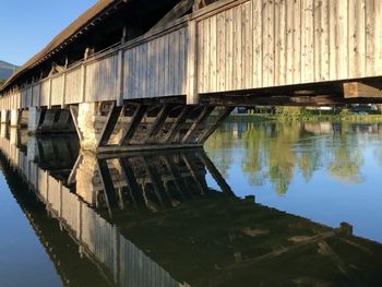 Bridge over river by old building against sky