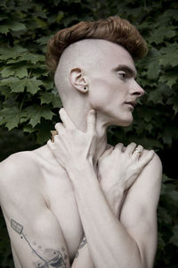 Close-up of shirtless young man by plants