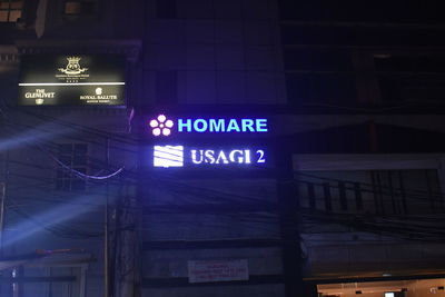 Low angle view of illuminated sign on building at night