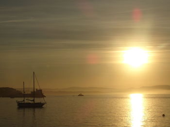 Silhouette of sailboat in sea during sunset