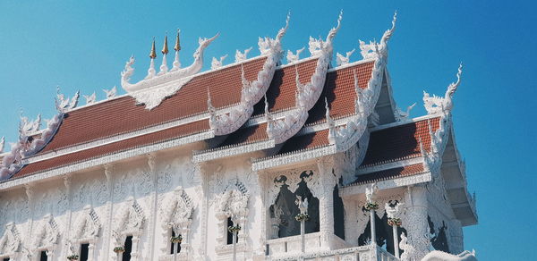 Low angle view of sculptures on building against clear blue sky