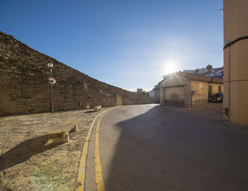 Empty road by buildings against sky