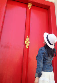 Woman looking up to the gorgeous red colored wooden door of the buddhist temple