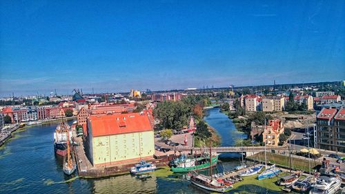 High angle view of cityscape by sea against clear blue sky