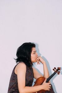 Young woman playing guitar against white background