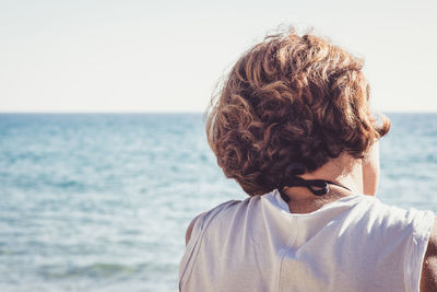 Rear view of man standing at beach against clear sky