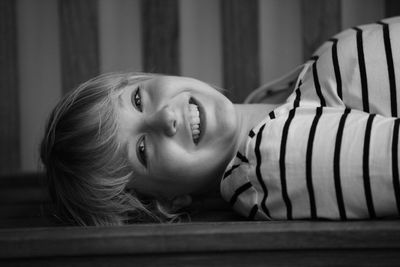 Portrait of smiling teenage girl lying on bench at home