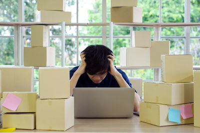 Rear view of woman using phone while sitting on table