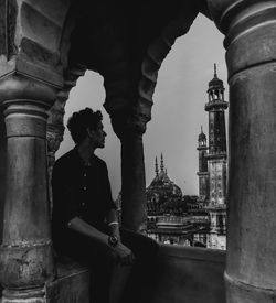 Young man sitting at historic building