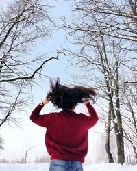 Rear view of woman standing against bare tree