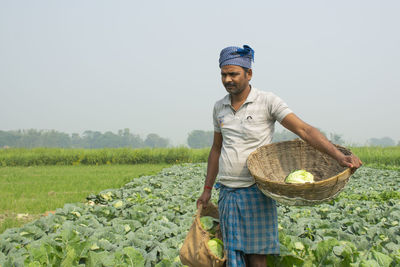 Farmer carrying basket of vegetable at farm land