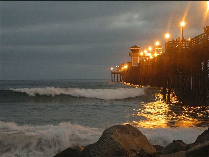 sea, water, beach, building exterior, sky, built structure, architecture, shore, illuminated, wave, cloud - sky, night, sunset, sand, dusk, street light, scenics, nature, surf, city