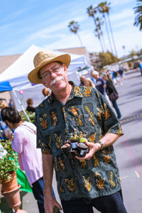 Portrait of happy man holding potted plants in market