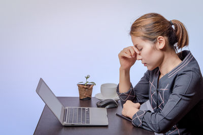 Young woman using mobile phone while sitting on table