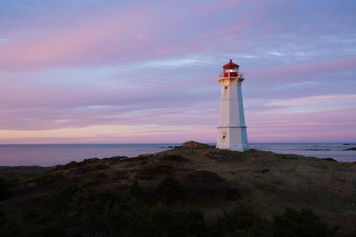 Lighthouse by sea against sky
