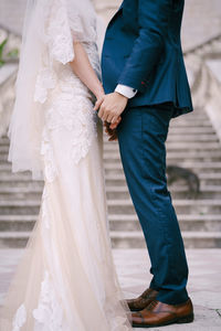 Low section of bridegroom holding hands