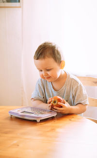 Side view of boy using toy tablet while sitting at home