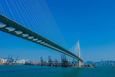 Low angle view of bridge over sea against clear blue sky