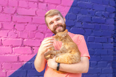 Portrait of smiling young man holding wall