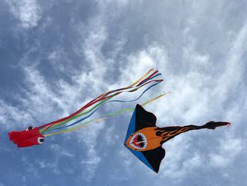 Low angle view of kites flying against sky