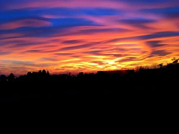 Silhouette landscape against orange sky