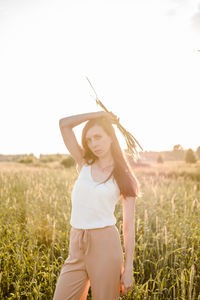 Full length of young woman standing on field against sky